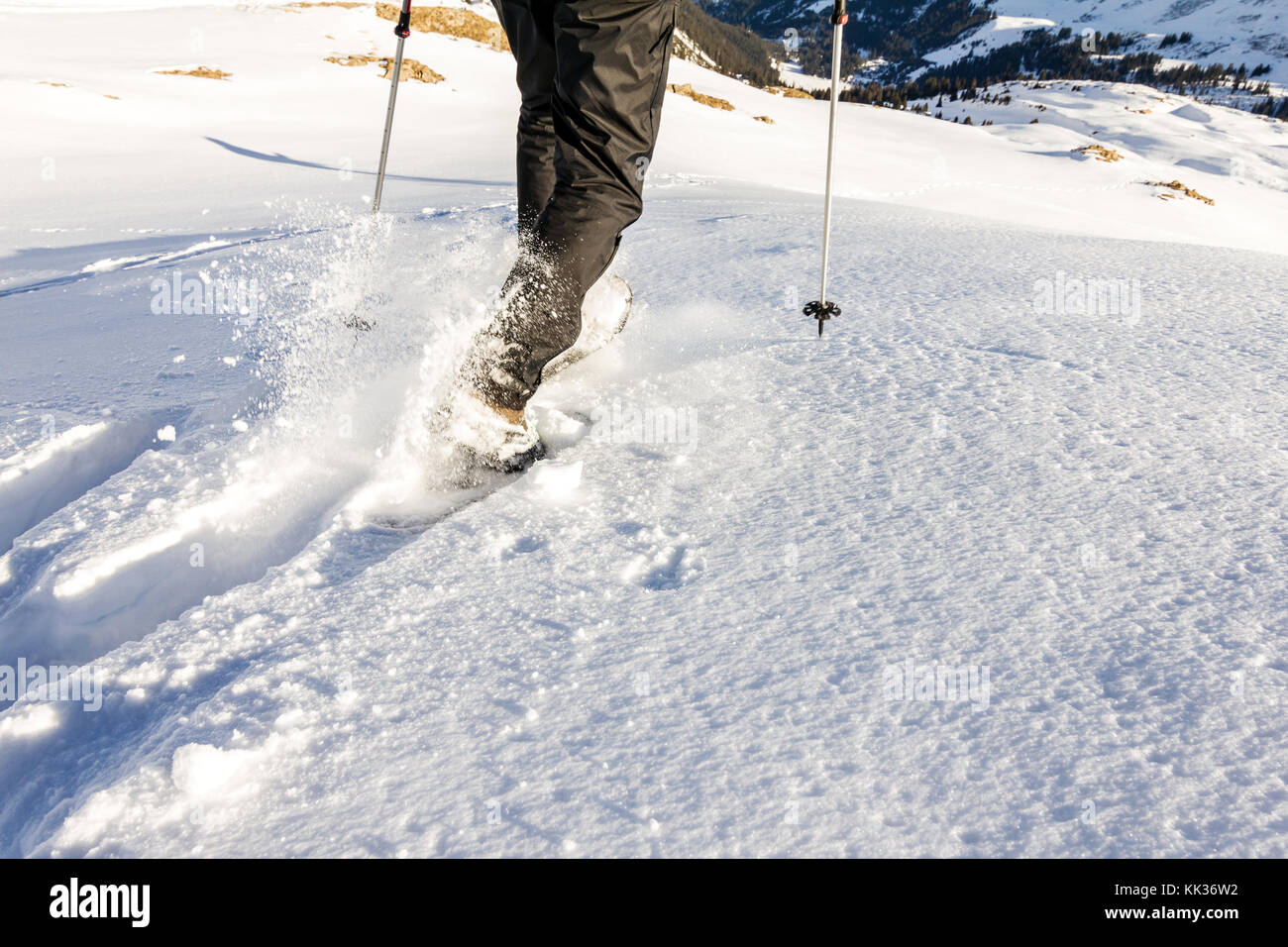 Man running downhill through deep snow with snoeshoes and hiking sticks. Stock Photo