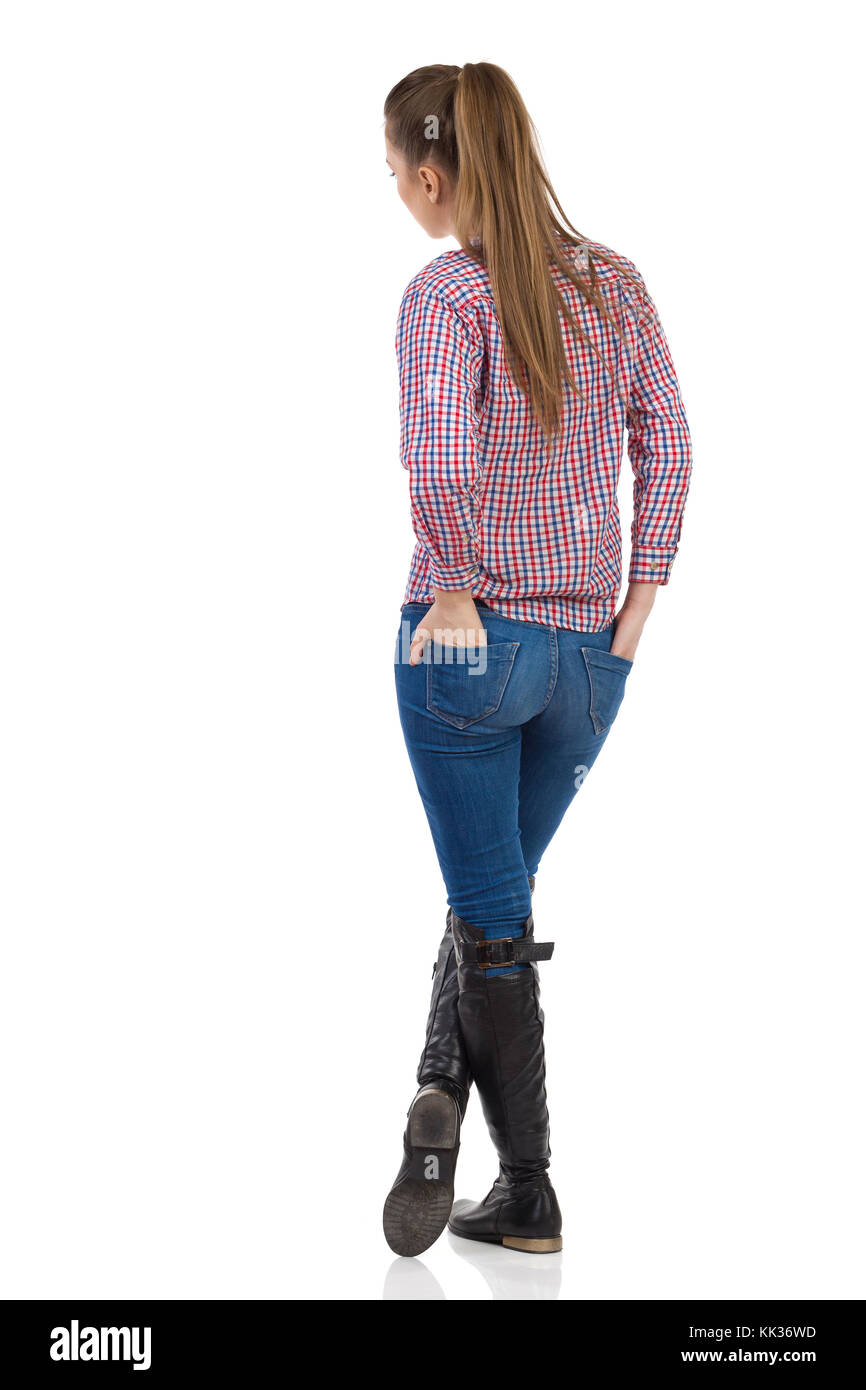 Young woman in jeans, black boots and lumberjack shirt standing with