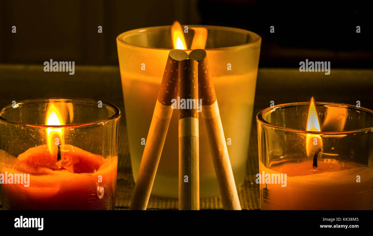 Different configurations with cigarettes and burning candles Stock
