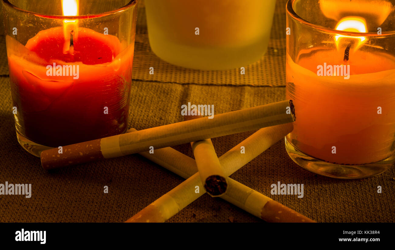 Different configurations with cigarettes and burning candles Stock