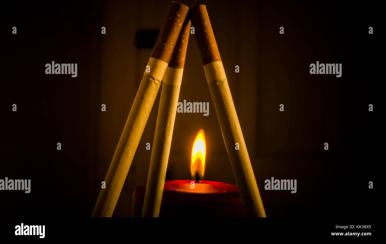 Different configurations with cigarettes and burning candles Stock