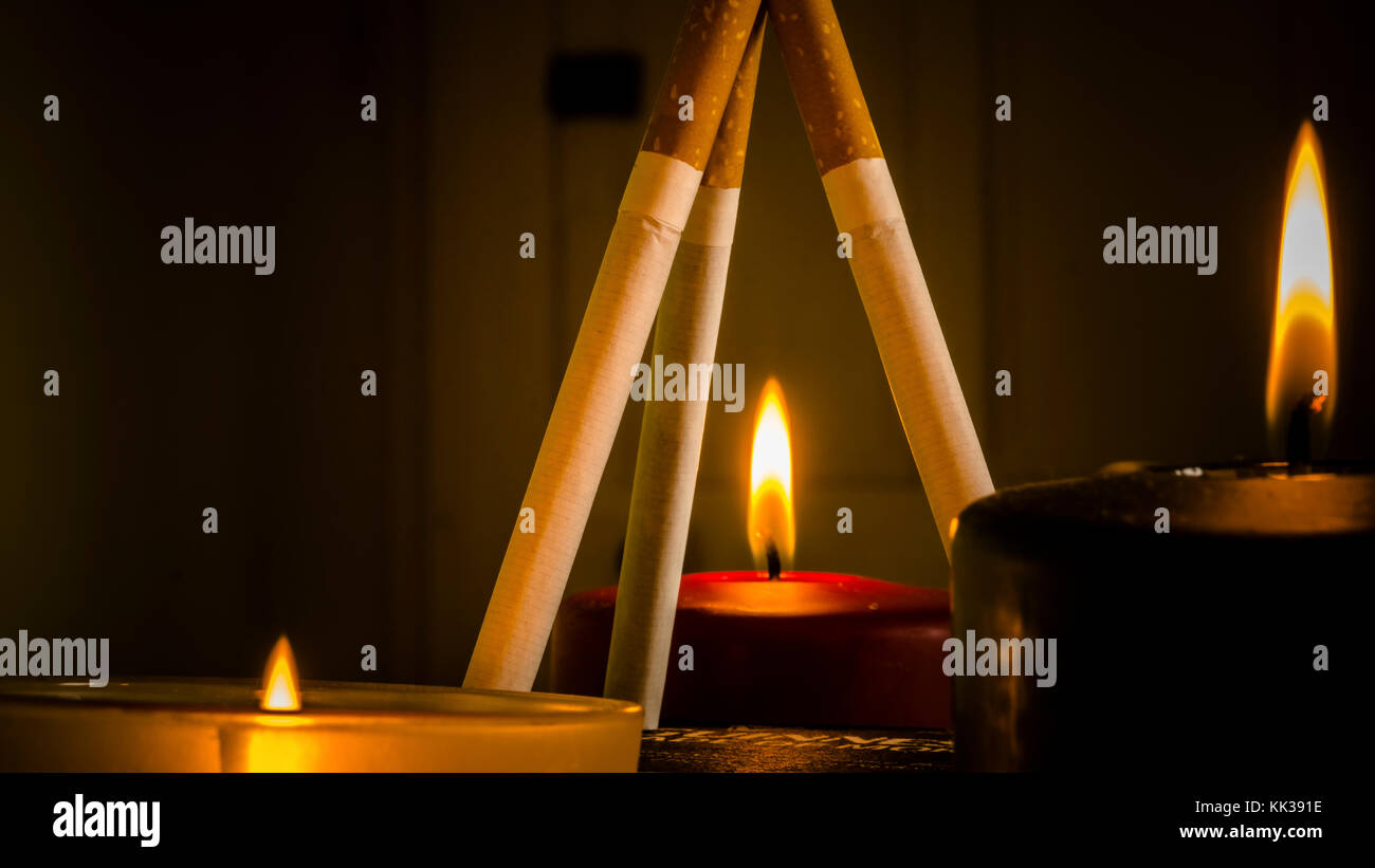 Different configurations with cigarettes and burning candles Stock