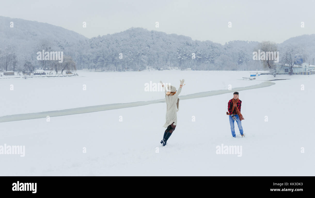 A couple of lovers are having fun by throwing snowballs in the meadow ...