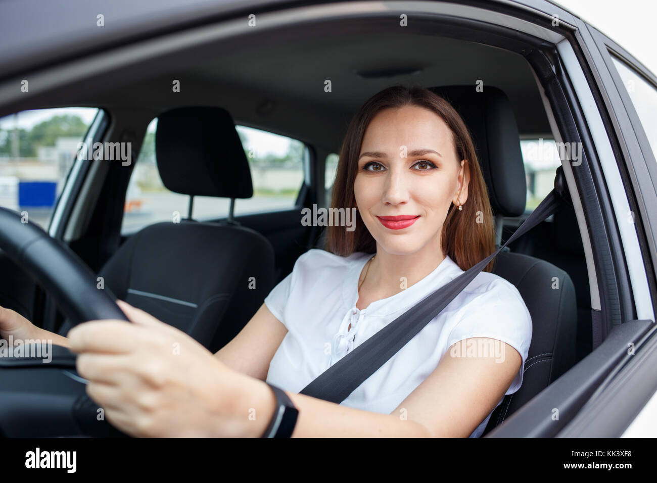 Young woman in white shirt driving car on the road. Hispanic girl ...