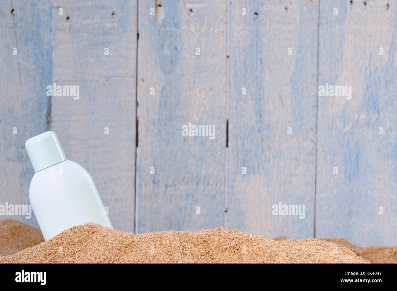 Bottle in sand against of blue wooden wall Stock Photo
