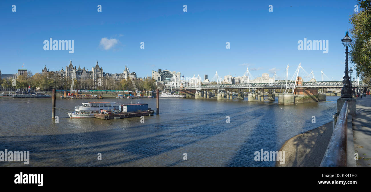 View across the river Thames , with the Golden Jubilee and Hungerford bridges, Charing Cross station, Whitehall and the Ministry of Defence far left Stock Photo