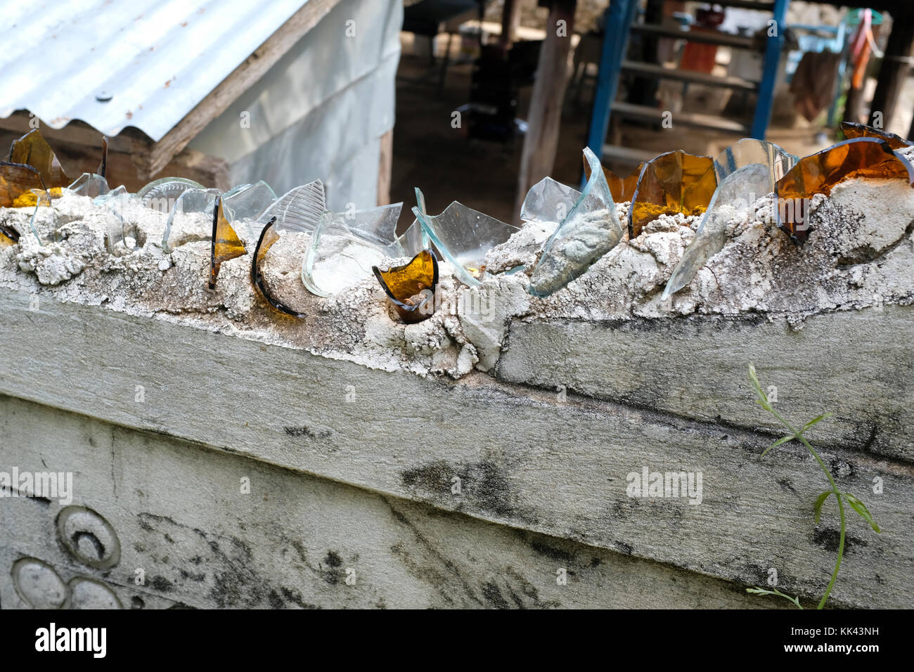 Broken Glass on top of wall as a security fence in Mandalay, Myanmar Stock Photo