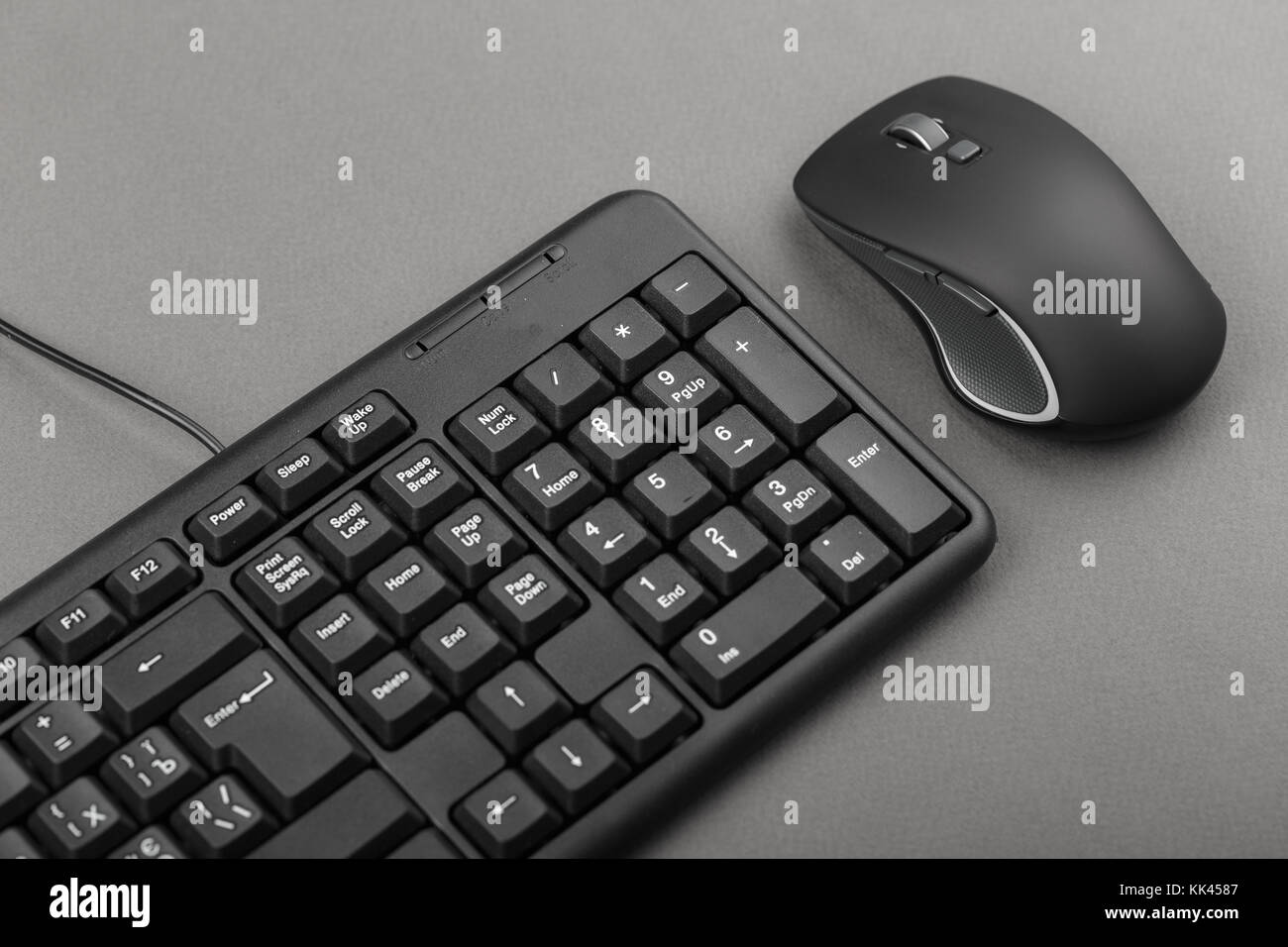 black computer mouse near the keyboard, office equipment on the table
