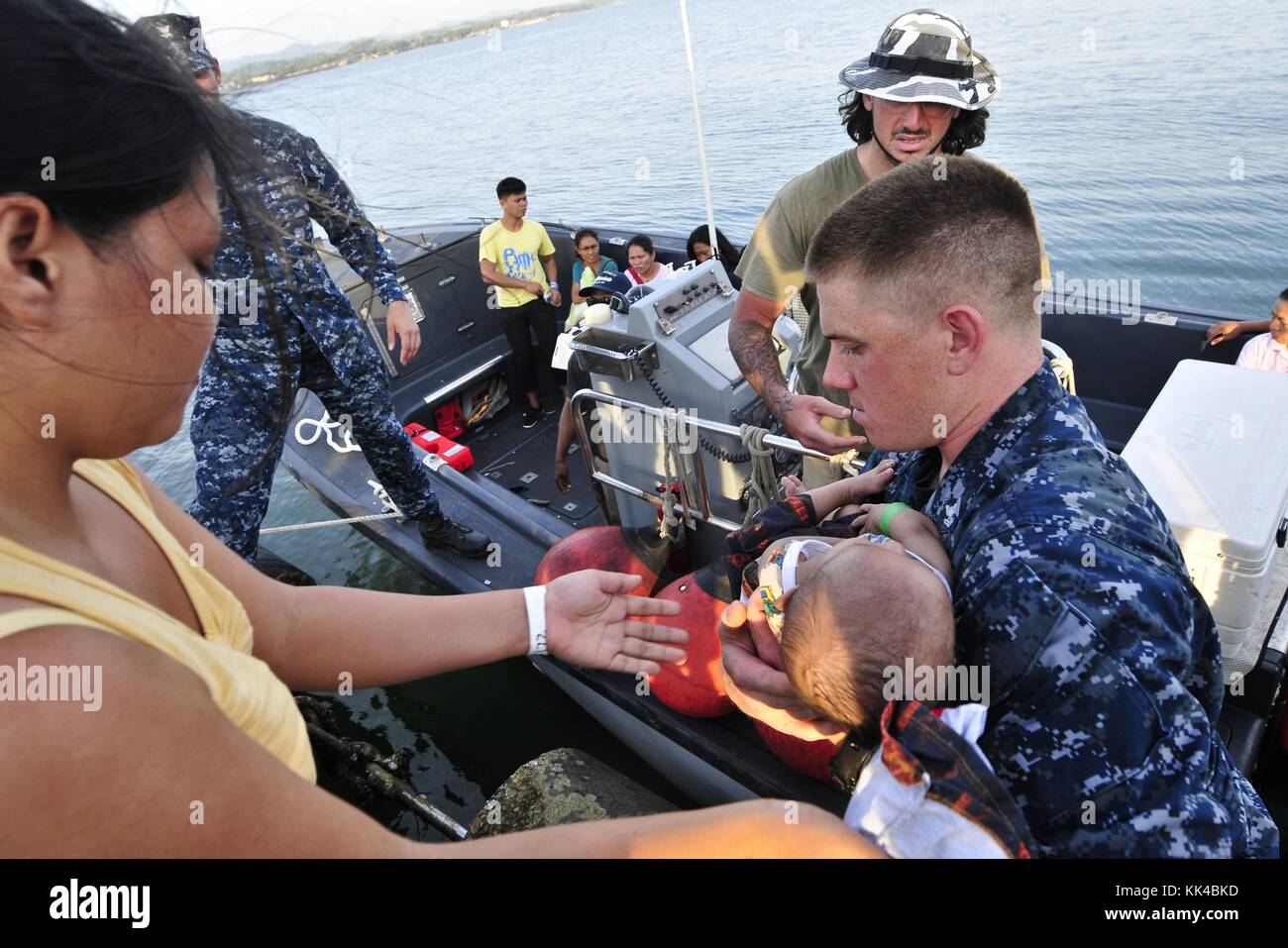 Hospital Corpsman 2nd Class Kyle Turner assists in transporting an infant patient into a Band-Aid boat assigned to the Military Sealift Command hospital ship USNS Mercy T-AH 19 during Pacific Partnership 2012, Samar, Philippines, 2012. Image courtesy Kristopher Radder/US Navy. Stock Photo