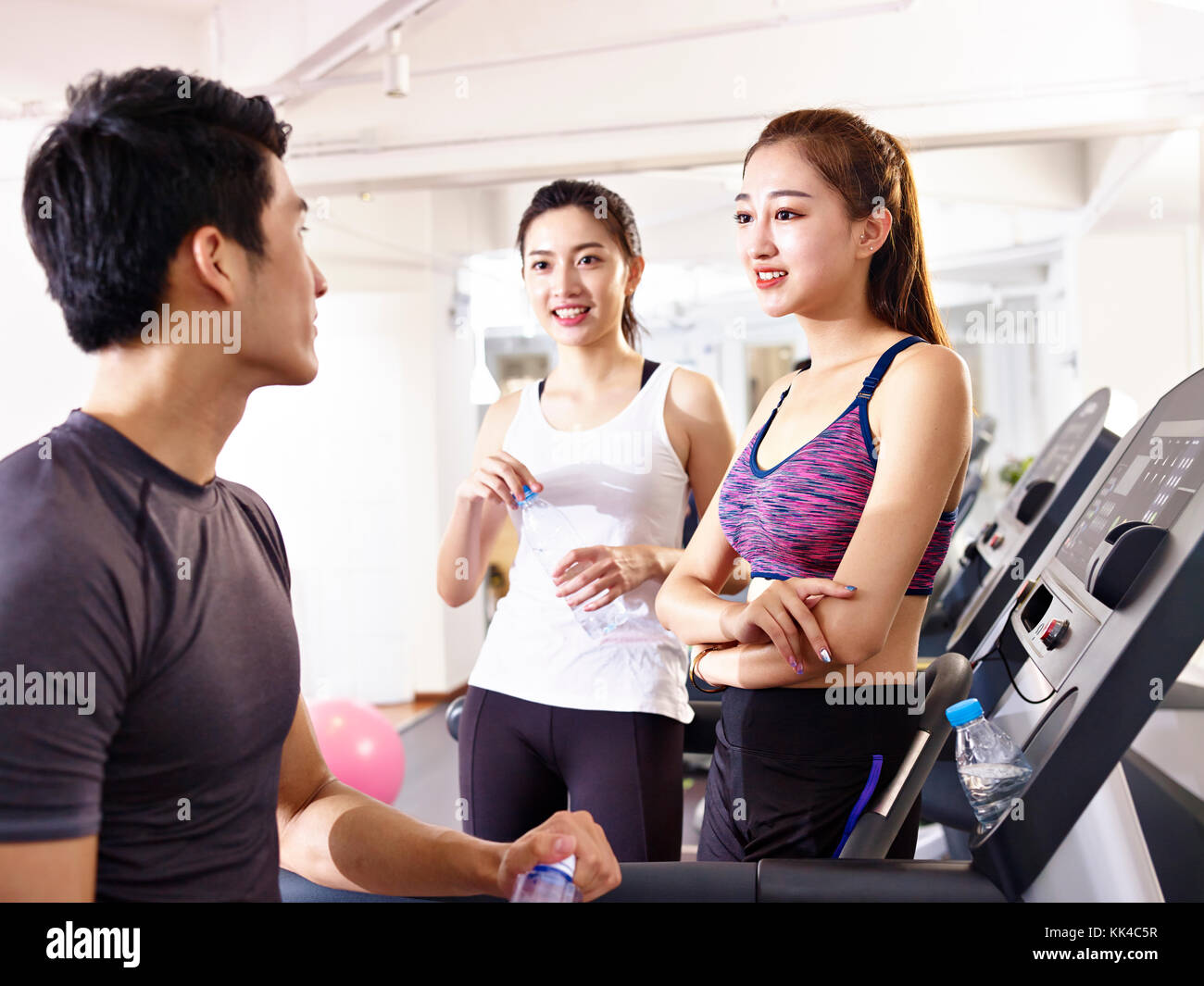 young asian man and women chatting in gym while taking a break. Stock Photo