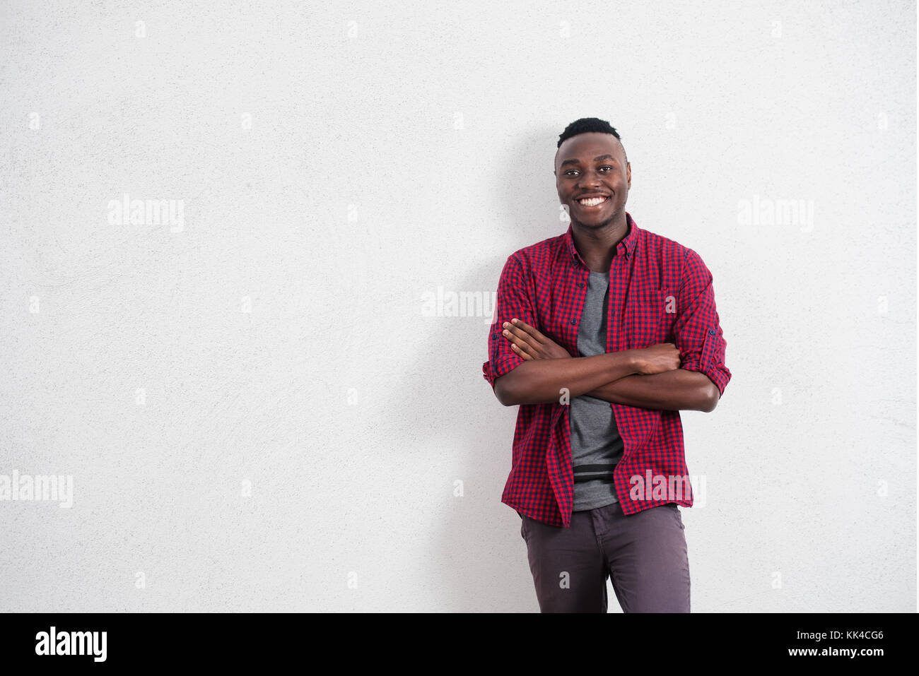 People and lifestyle concept. Portrait of happy and positive young African male in good mood, wearing red shirt smiling cheerfully showing his perfect Stock Photo