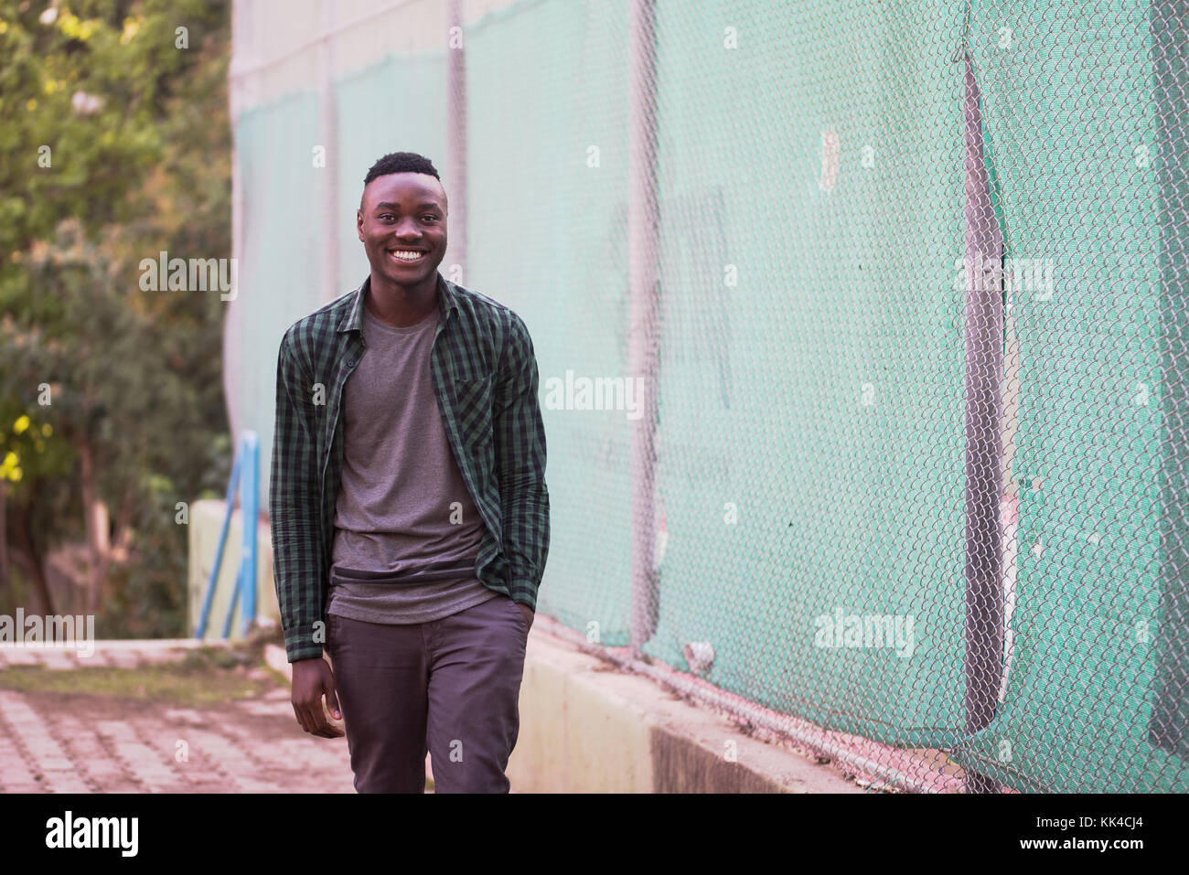Portrait of stylish african american young man on sportswear,green shirt walking. Black men model street fashion. Stock Photo