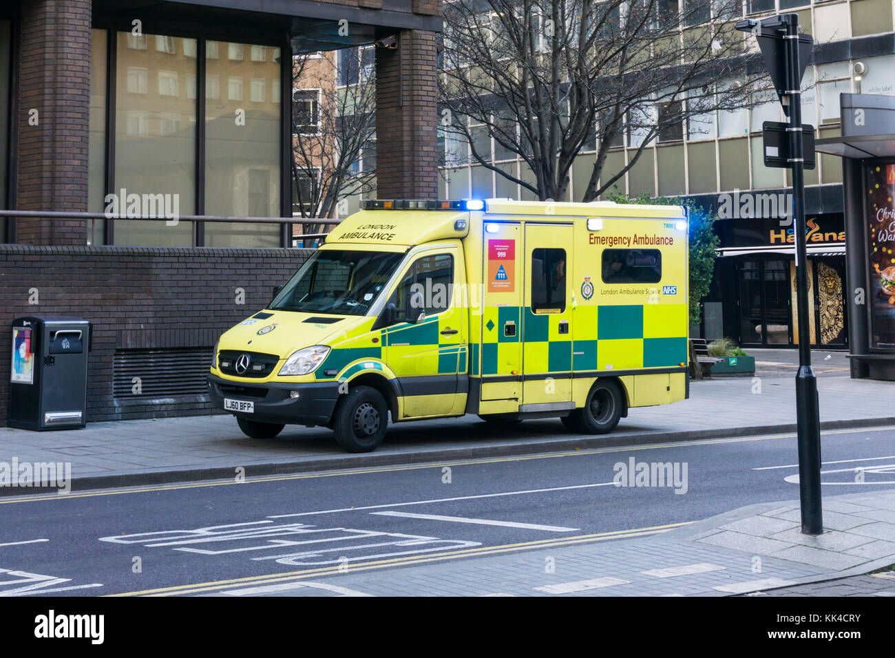 An emergeny ambulance of the London Ambulance Service parked with blue lights flashing in the