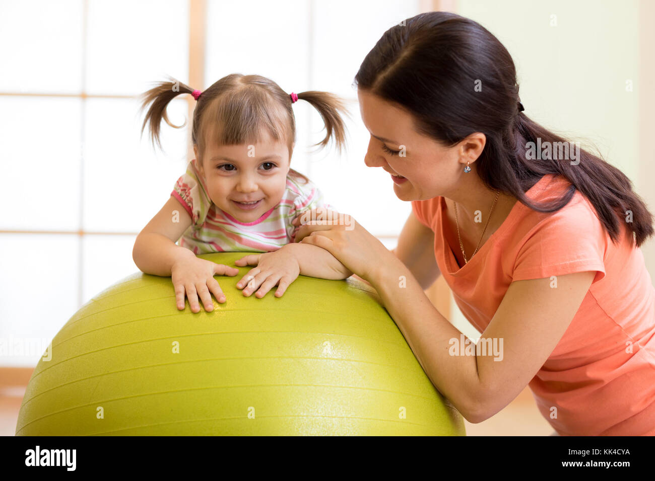 Mother with happy kid doing exercises with gymnastic ball at fitness class. Concept of caring for the baby's health. Stock Photo