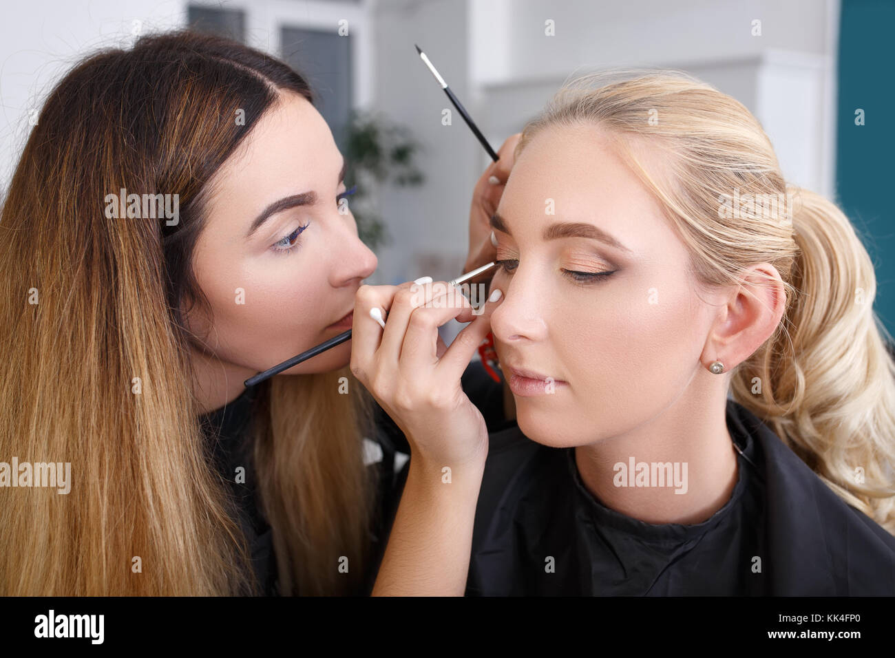 professional makeup artist doing makeup for young woman. Eye makeup