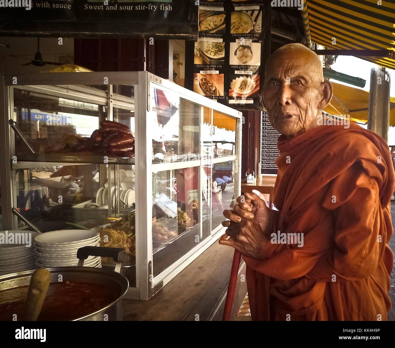 Siem Reap. A monk in a street shop. -  11/12/2009  -  Cambodia / Angkor  -  Siem Reap. A monk in a street shop. -  Breakfast time!   -  Sylvain Leser / Le Pictorium Stock Photo