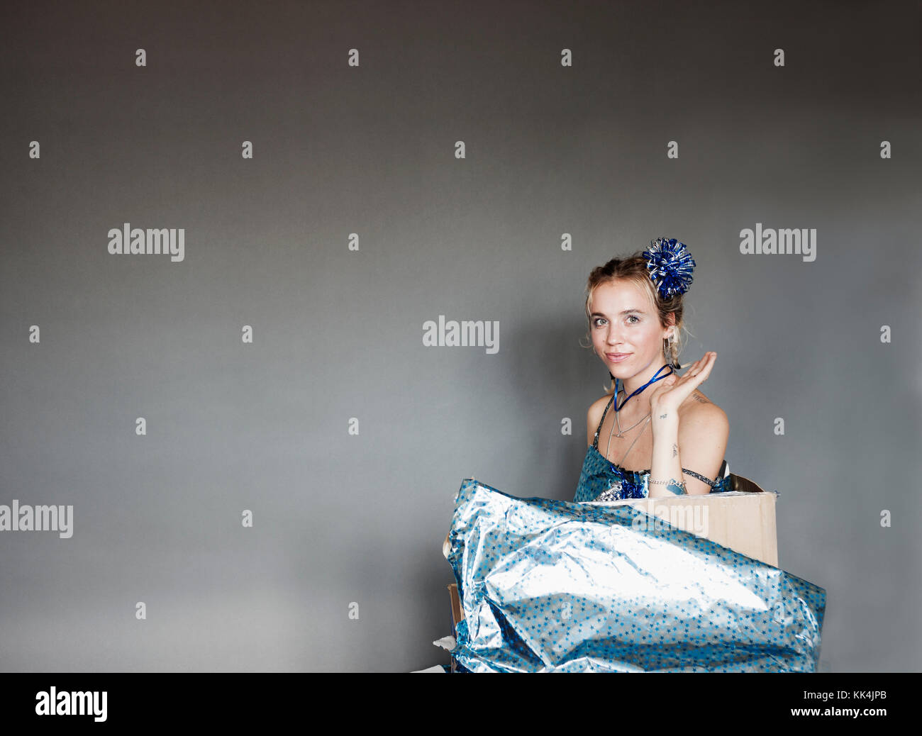 Young woman emerging from gift wrapped parcel cardboard box, with model release, London, 18/06/2017 Stock Photo