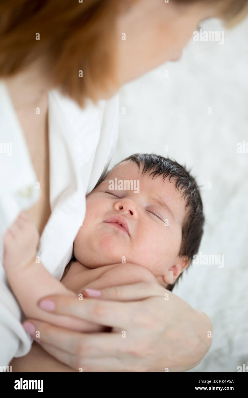 Mother holding her sleeping baby in bed Stock Photo