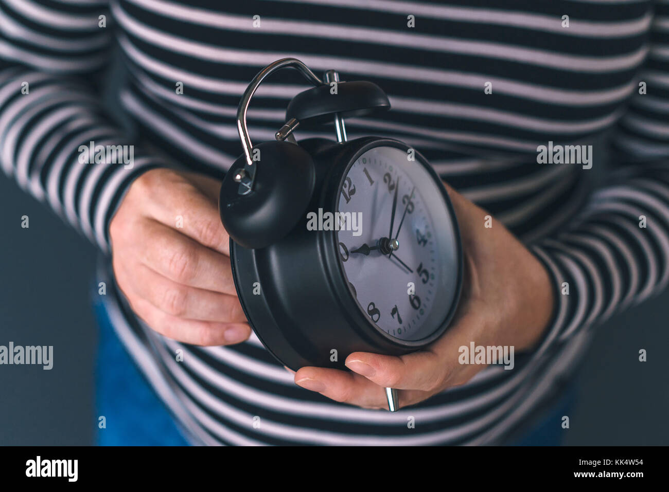 Woman winding retro alarm clock, concept of daylight saving time, selective focus Stock Photo