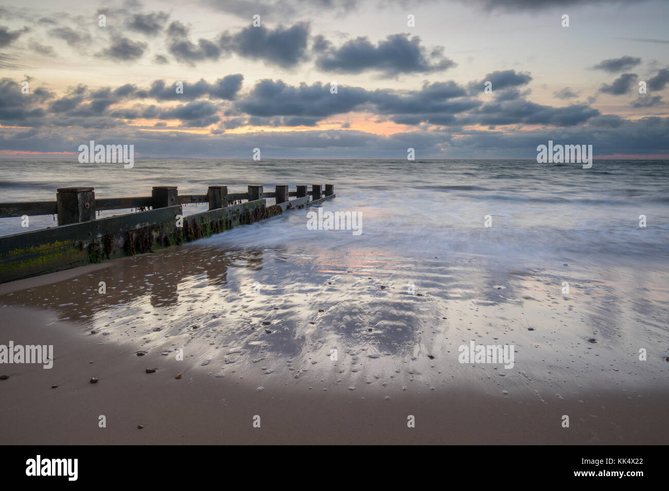 sunrise over groynes in bay Stock Photo - Alamy