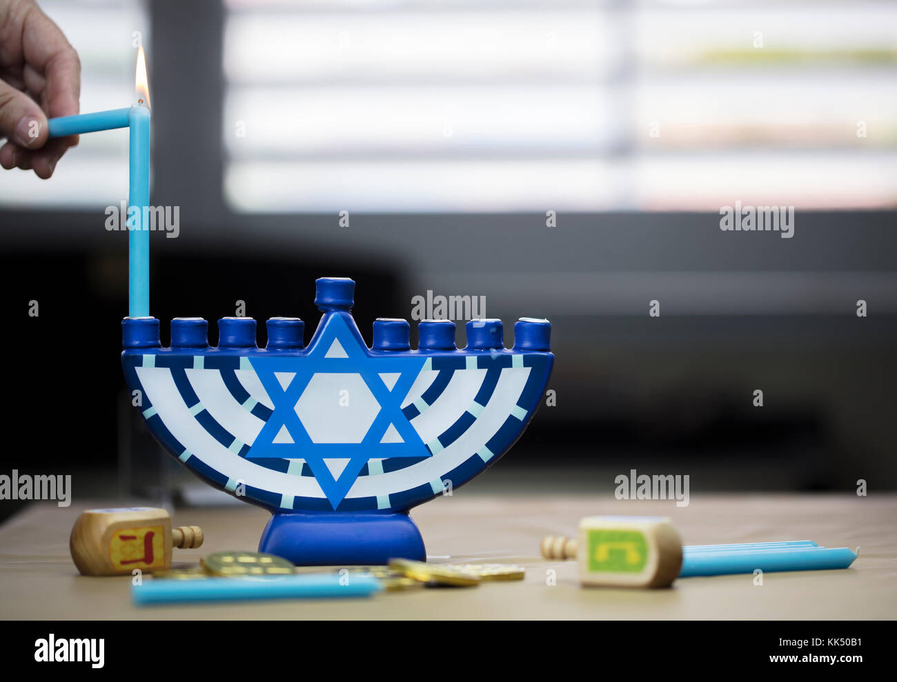 Hanukkah candles lit for the holiday celebration surrounded by dreidels and chocolate coins Stock Photo
