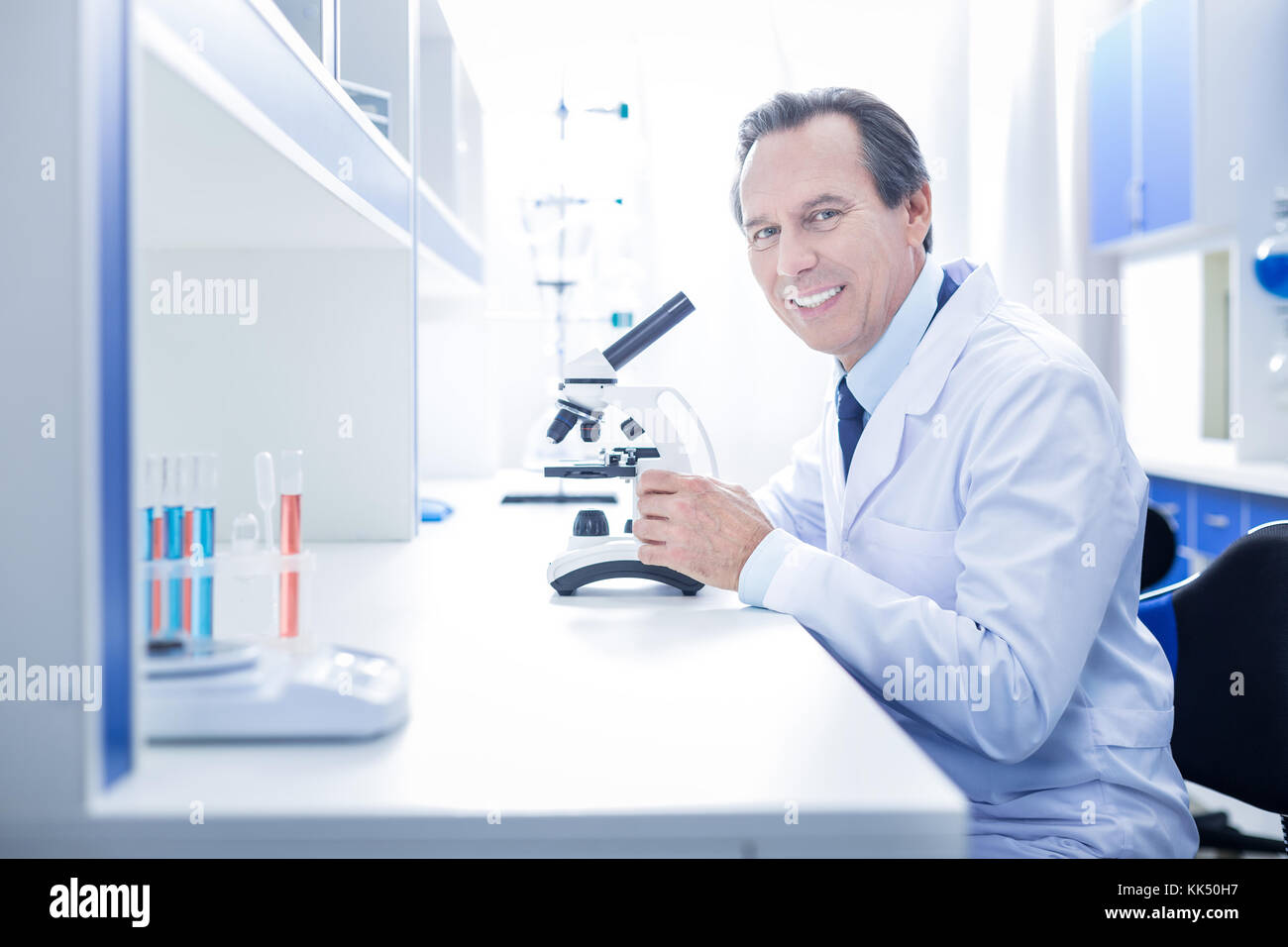 Happy positive scientist sitting at the table Stock Photo