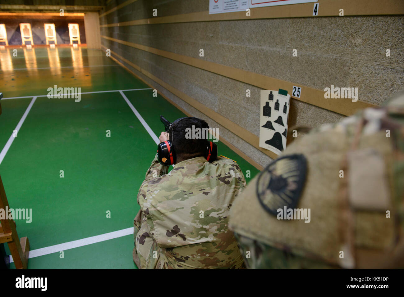 A U.S. Soldier with the 650th Military Intelligence Group acts as safety and oversees one of her peers who performs M9 pistol qualification at the Training Support Center Benelux 25-meter indoor range, on Chièvres Air Base, Belgium, Nov. 09, 2017. (U.S. Army photo by Visual Information Specialist Pierre-Etienne Courtejoie) Stock Photo