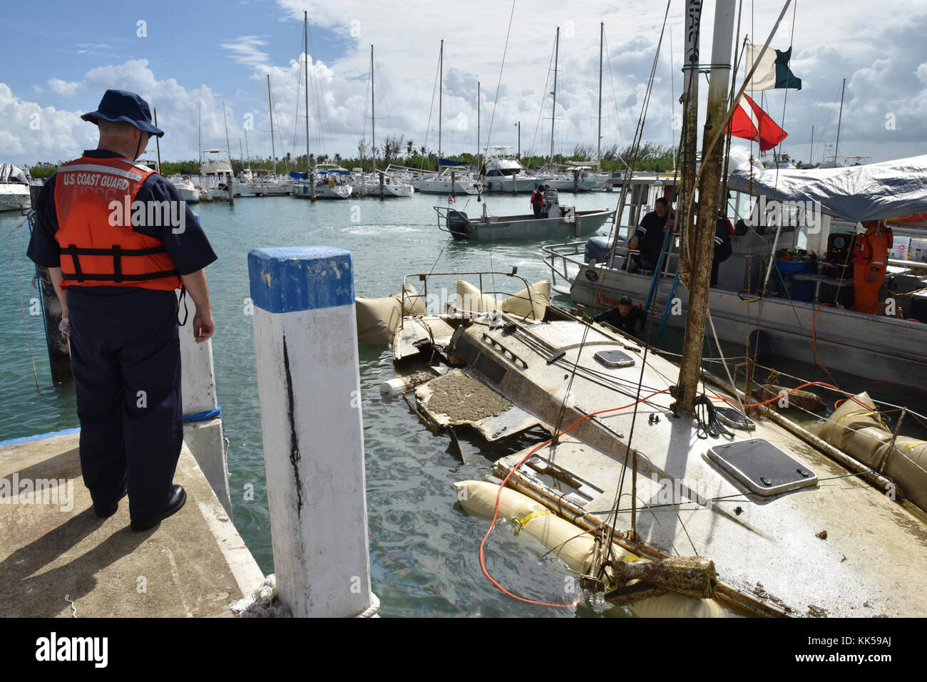 U.S. Coast Guard Chief Warrant Officer Christopher Runt observes a local salvage team as they refloat the sailing vessel Juyilanga at the Isleta Marina in Fajardo, Puerto Rico, on November 10, 2017. The dive team positioned salvage air bags underneath the vessel to refloat it after Hurricane Maria caused damage to the vessel’s starboard side. U.S. Coast Guard photo by Petty Officer 2nd Class Ali Flockerzi. Stock Photo