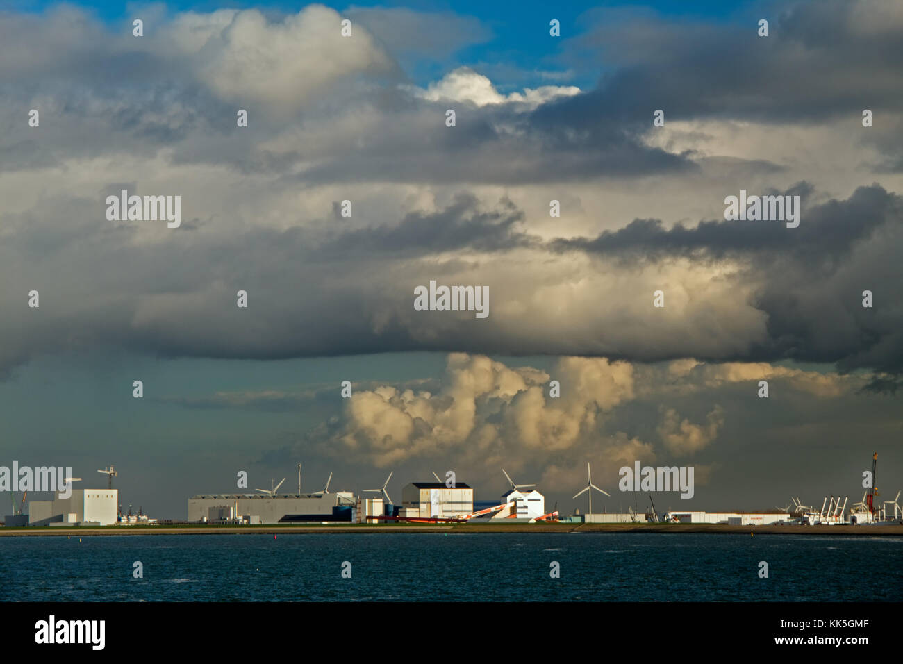 Coastline of the Dutch city Harlingen: windmills and factories under big clouds Stock Photo