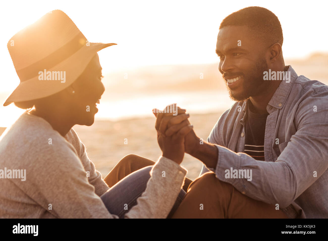 Romantic African couple sitting together on a beach at sunset Stock ...