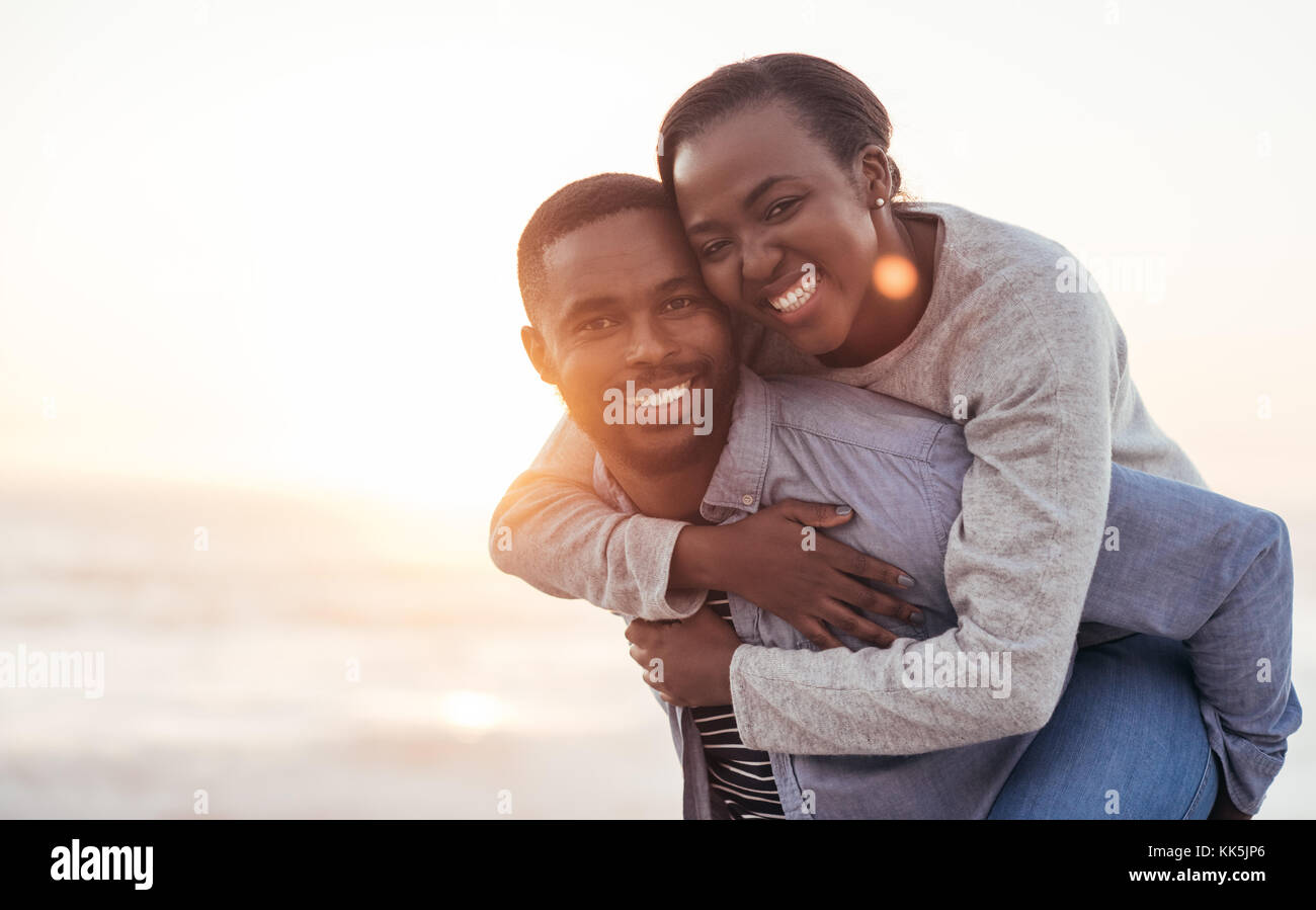 Smiling African couple enjoying a carefree day at the beach Stock Photo