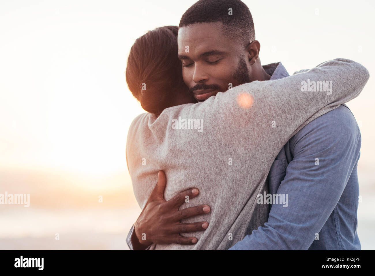 Happy young African couple embracing each other at the beach Stock Photo