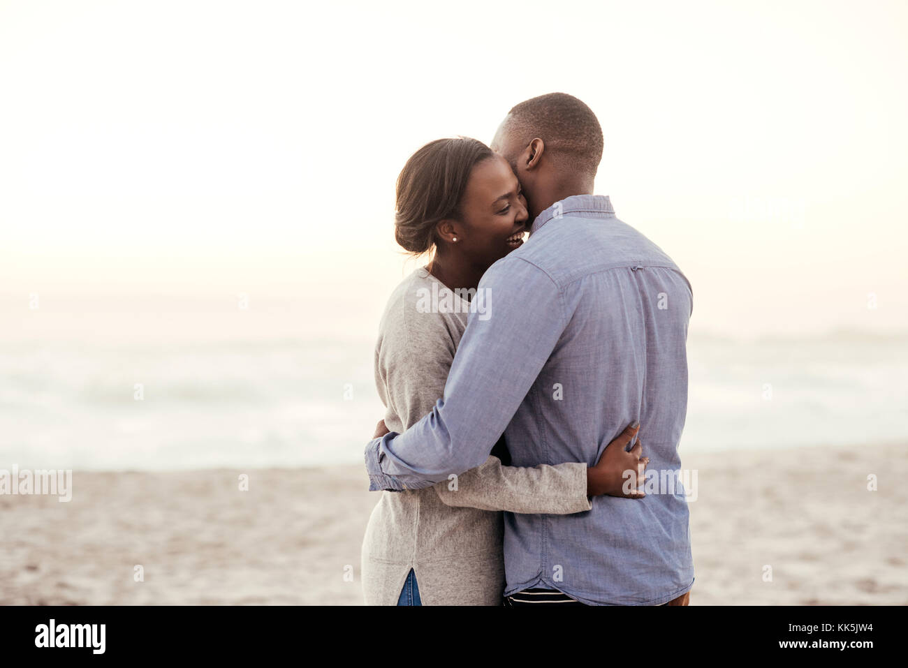 Happy young African couple embracing on a beach at dusk Stock Photo - Alamy