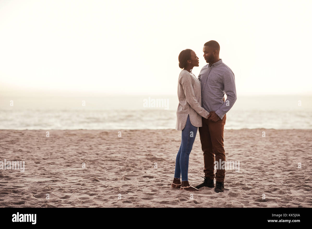 Content young African couple standing on a beach at dusk Stock Photo ...