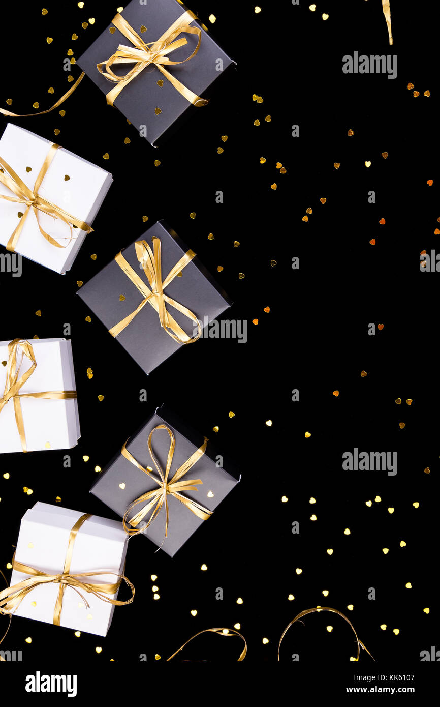 Black and white gift boxes with gold ribbon on shine background. Flat
