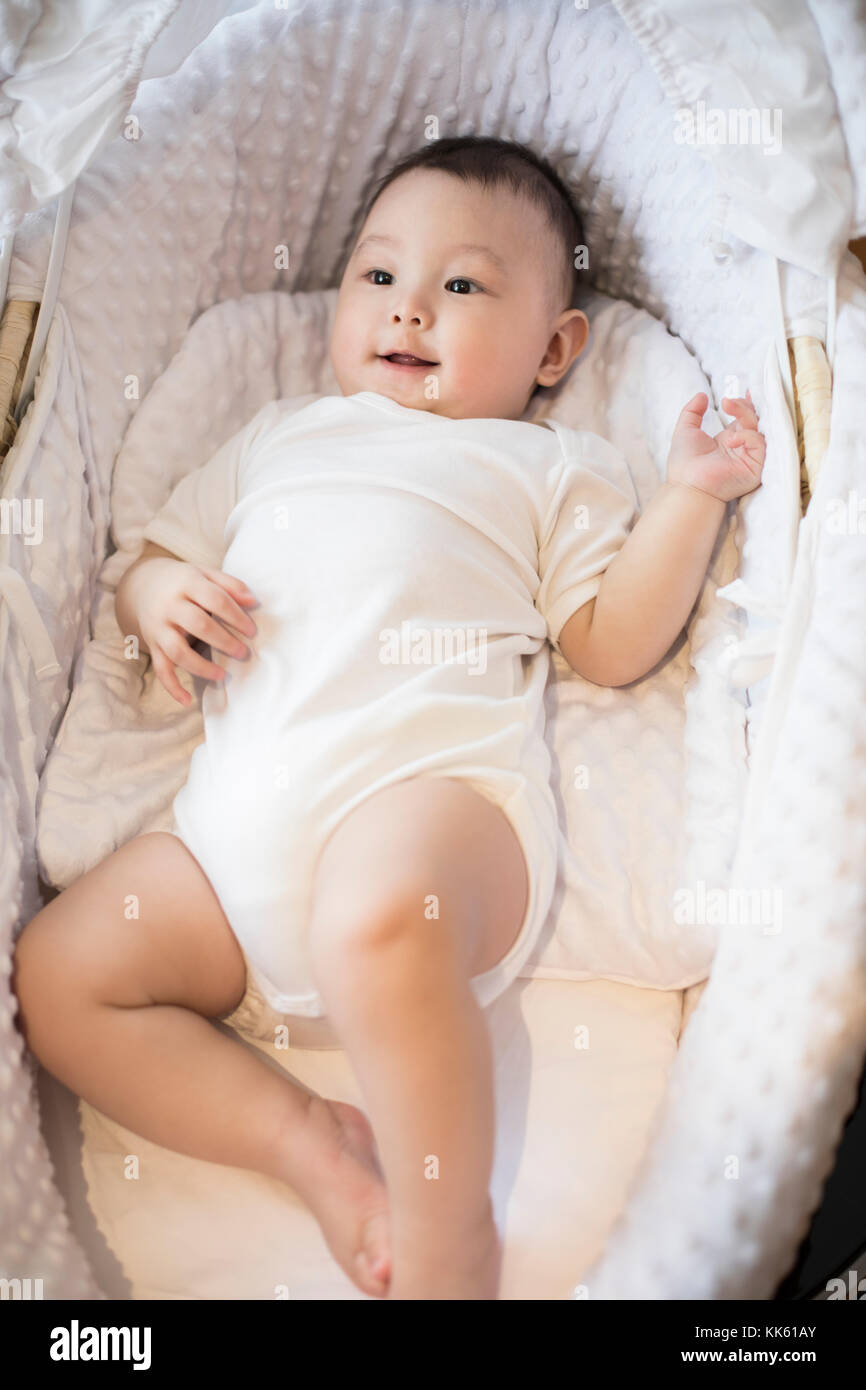 Cute Chinese baby lying in moses basket Stock Photo