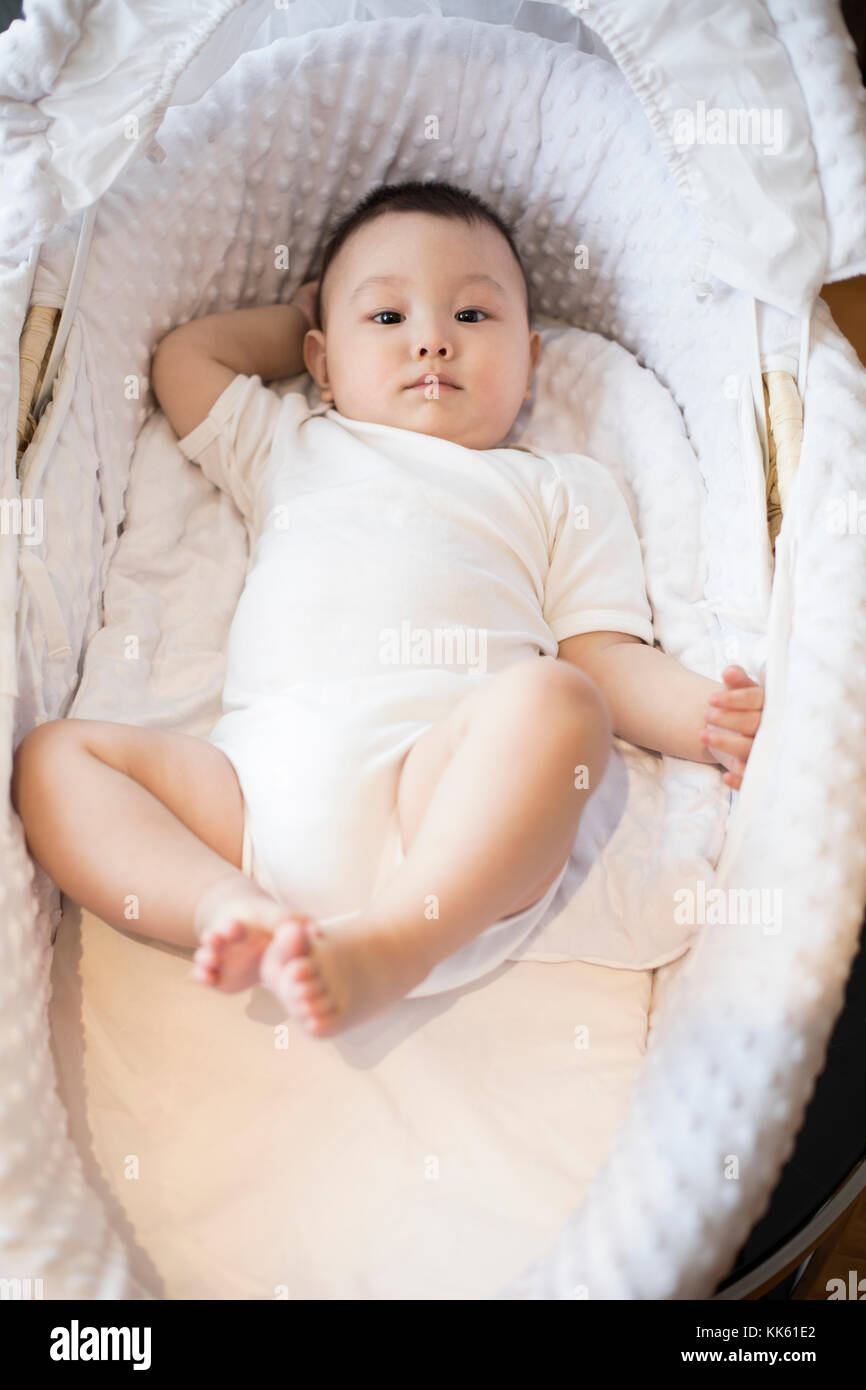 Cute Chinese baby lying in moses basket Stock Photo