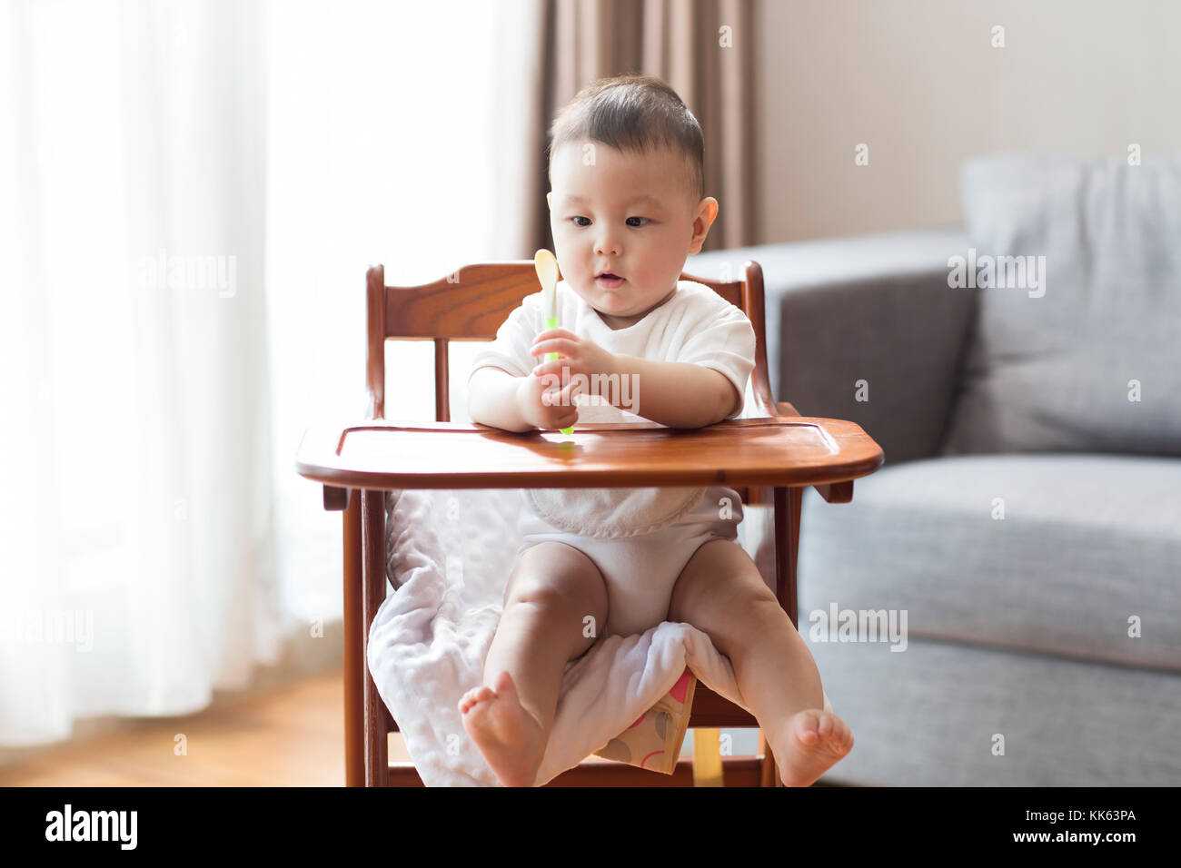 Cute Chinese baby boy sitting in high chair Stock Photo