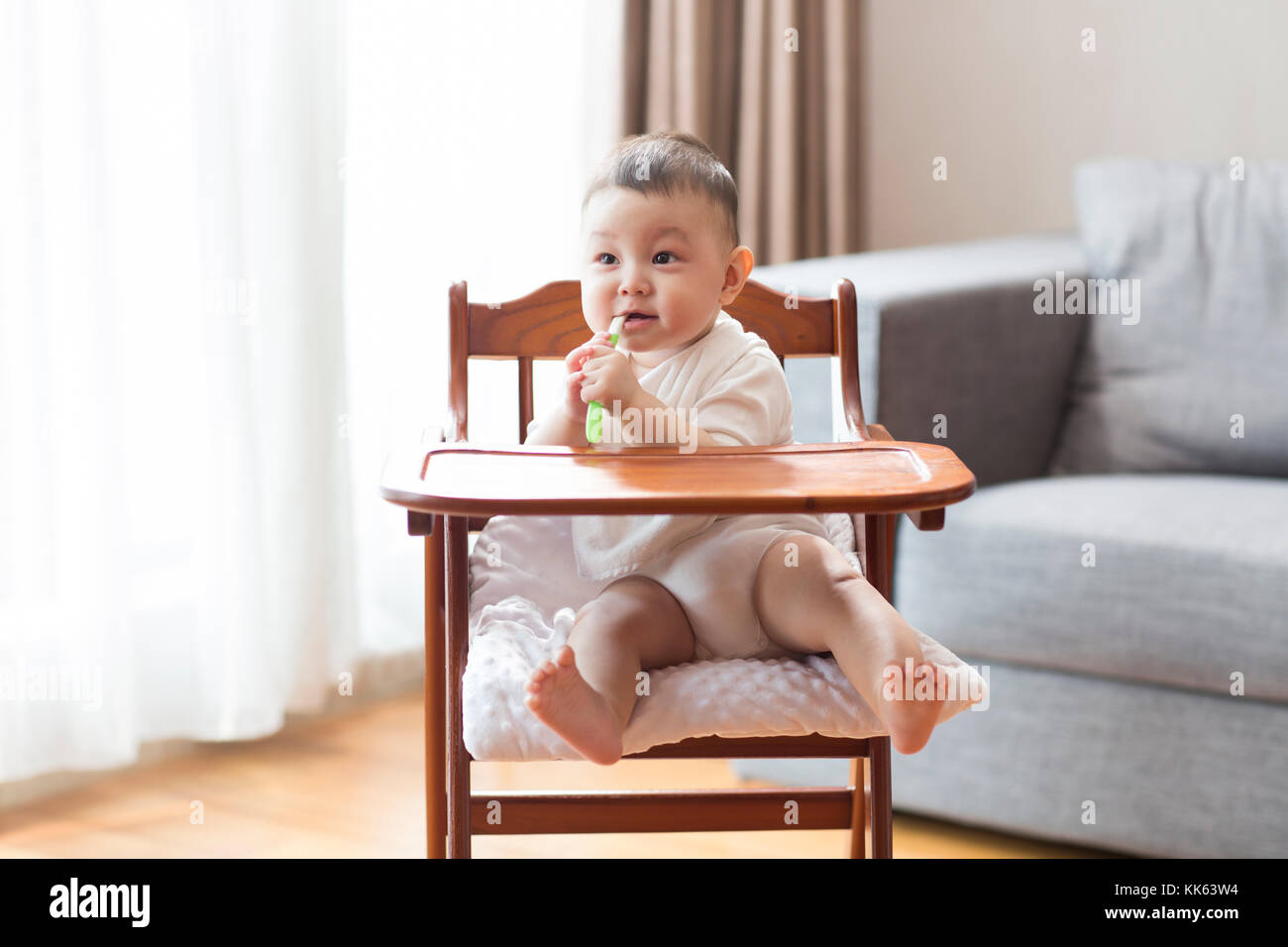 Cute Chinese baby boy sitting in high chair Stock Photo