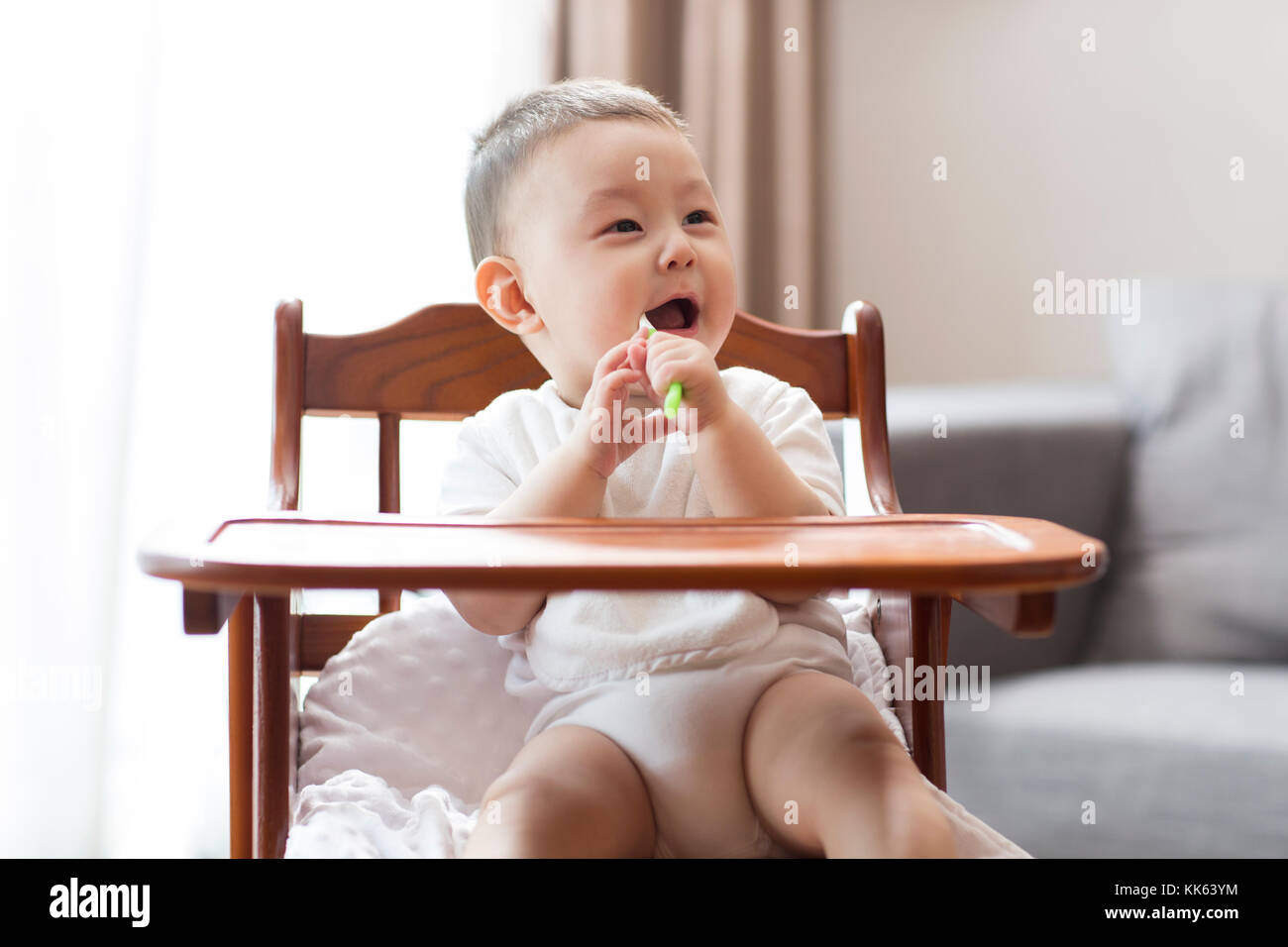 Cute Chinese baby boy sitting in high chair Stock Photo