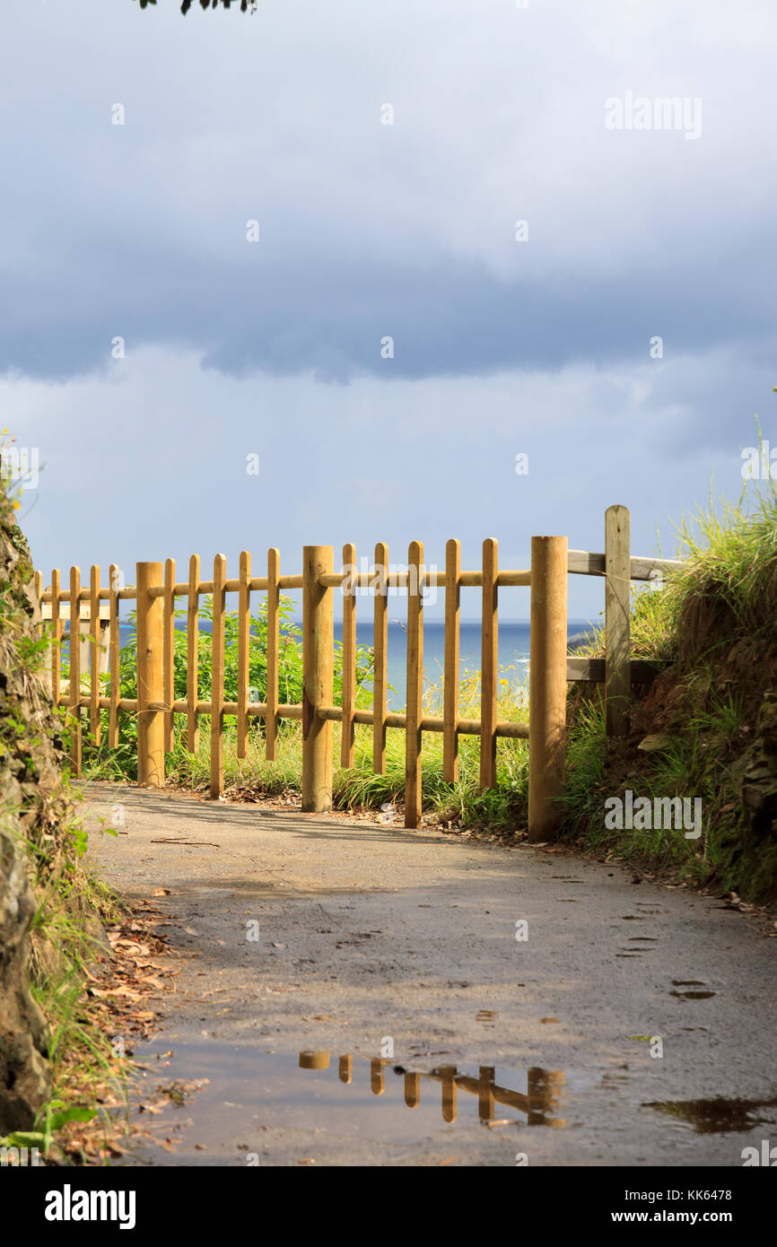Fence in a footpath near the sea with rocks around. Stock Photo