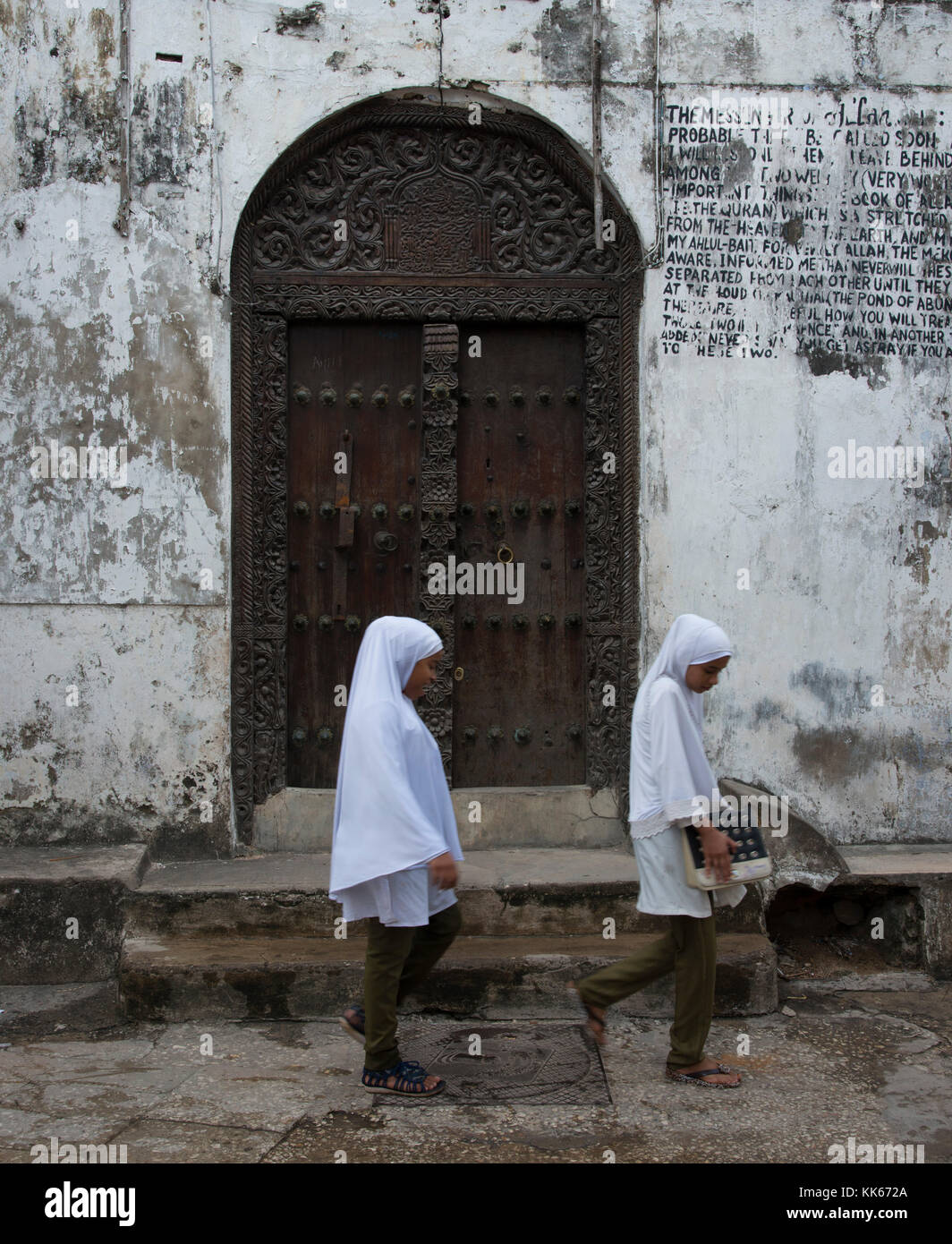 School girls passing an Indian door in Stone Town, Zanzibar, Tanzania, Africa Stock Photo