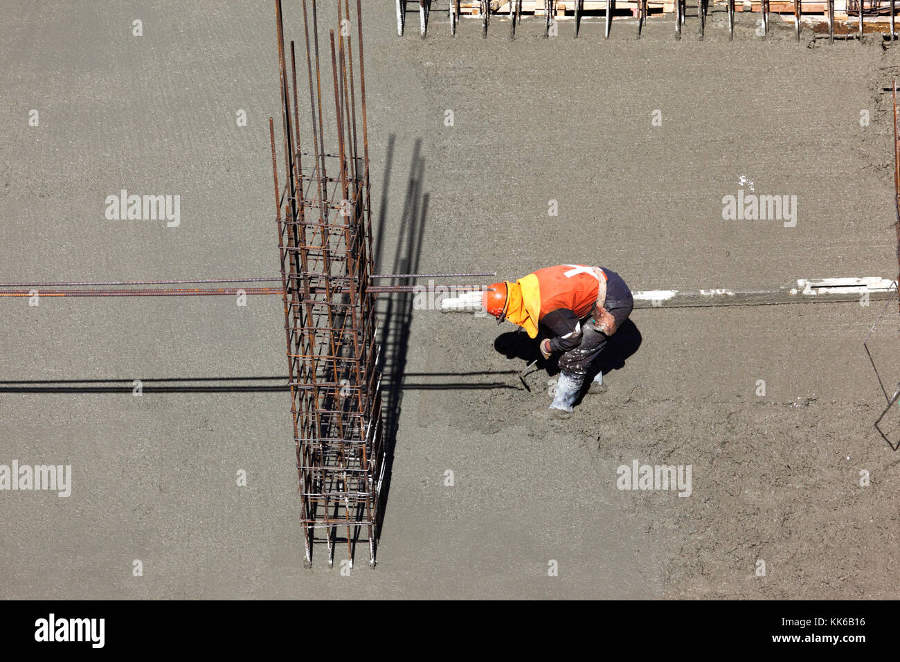 Worker on building site spreading wet concrete to make the floor of a high rise building, La Paz, Bolivia Stock Photo