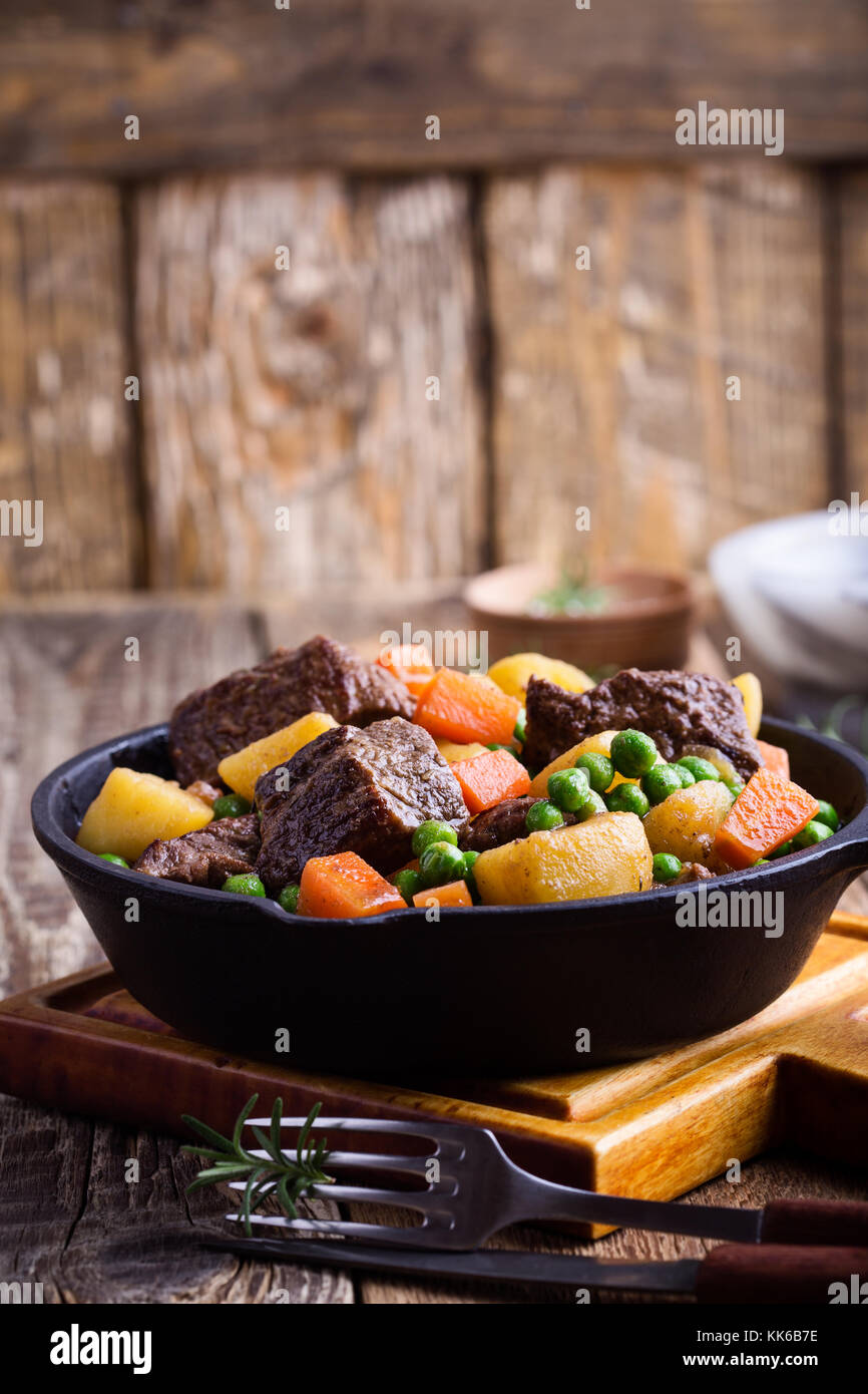 Beef and vegetable stew with potatoes in cast iron skillet on rural