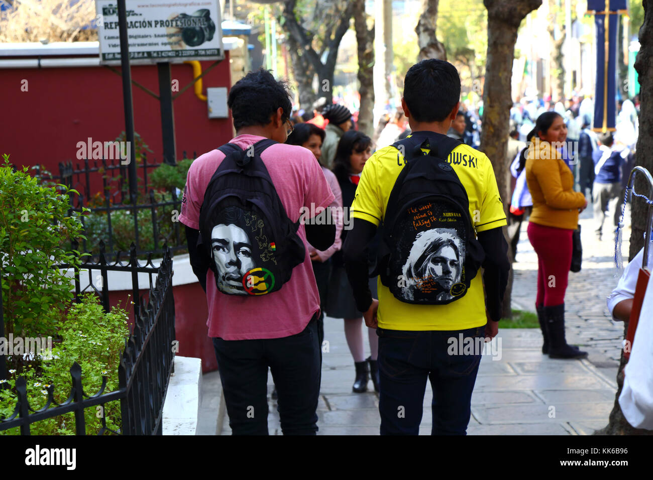 Youths wearing rucksacks with faces of Jimi Hendrix (L) and Kurt Cobain (R) on them walking in street, La Paz, Bolivia Stock Photo