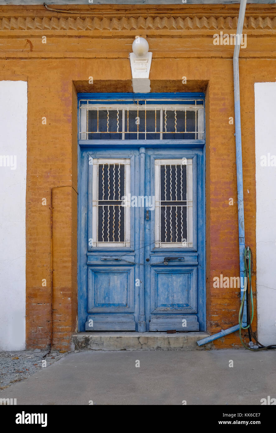 Old blue wooden doors in Cyprian village.  Framed by orange painted wall. Stock Photo