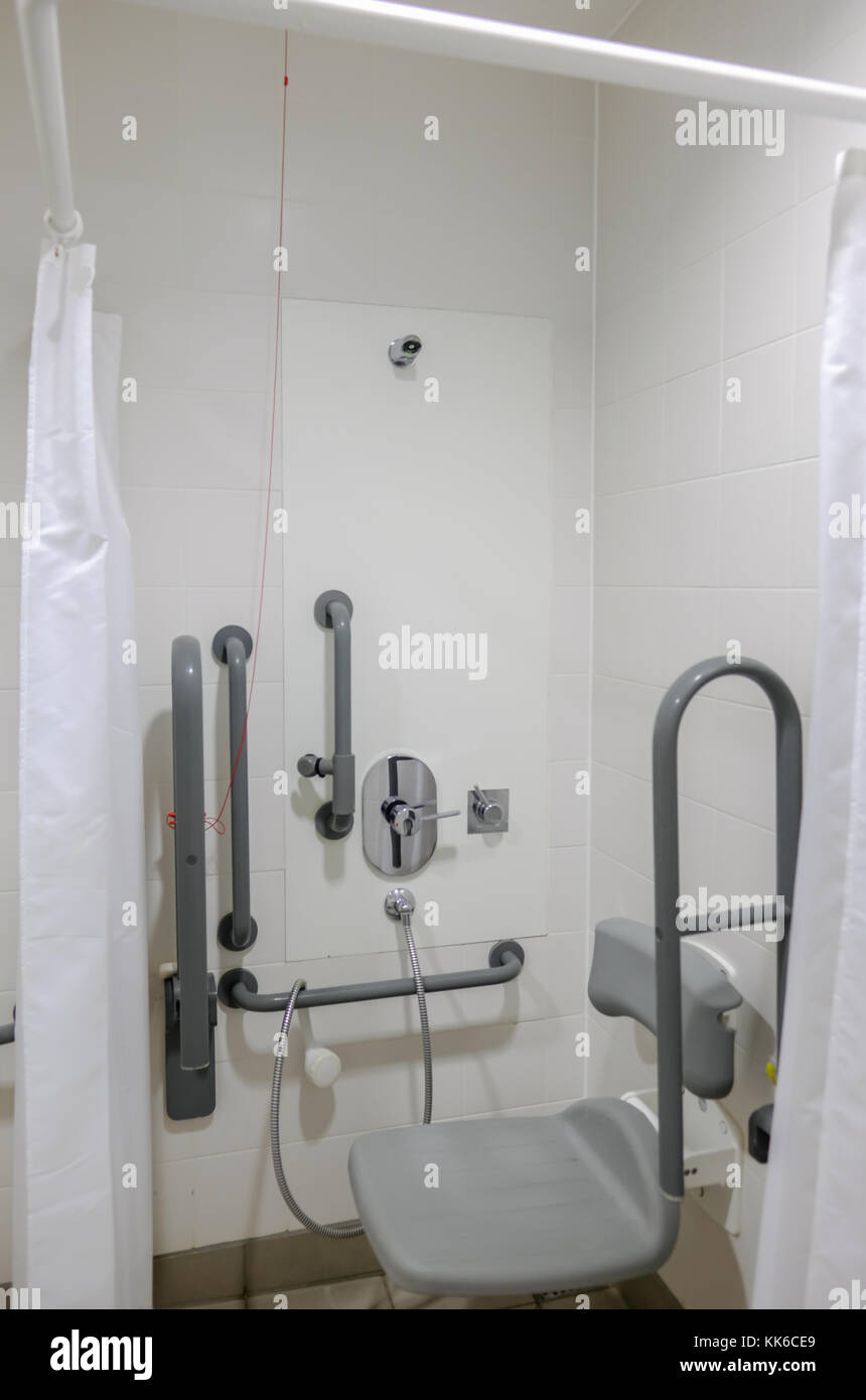 Disabled shower area with handrail and seat. Close up shot of empty accessible bathroom. Stock Photo