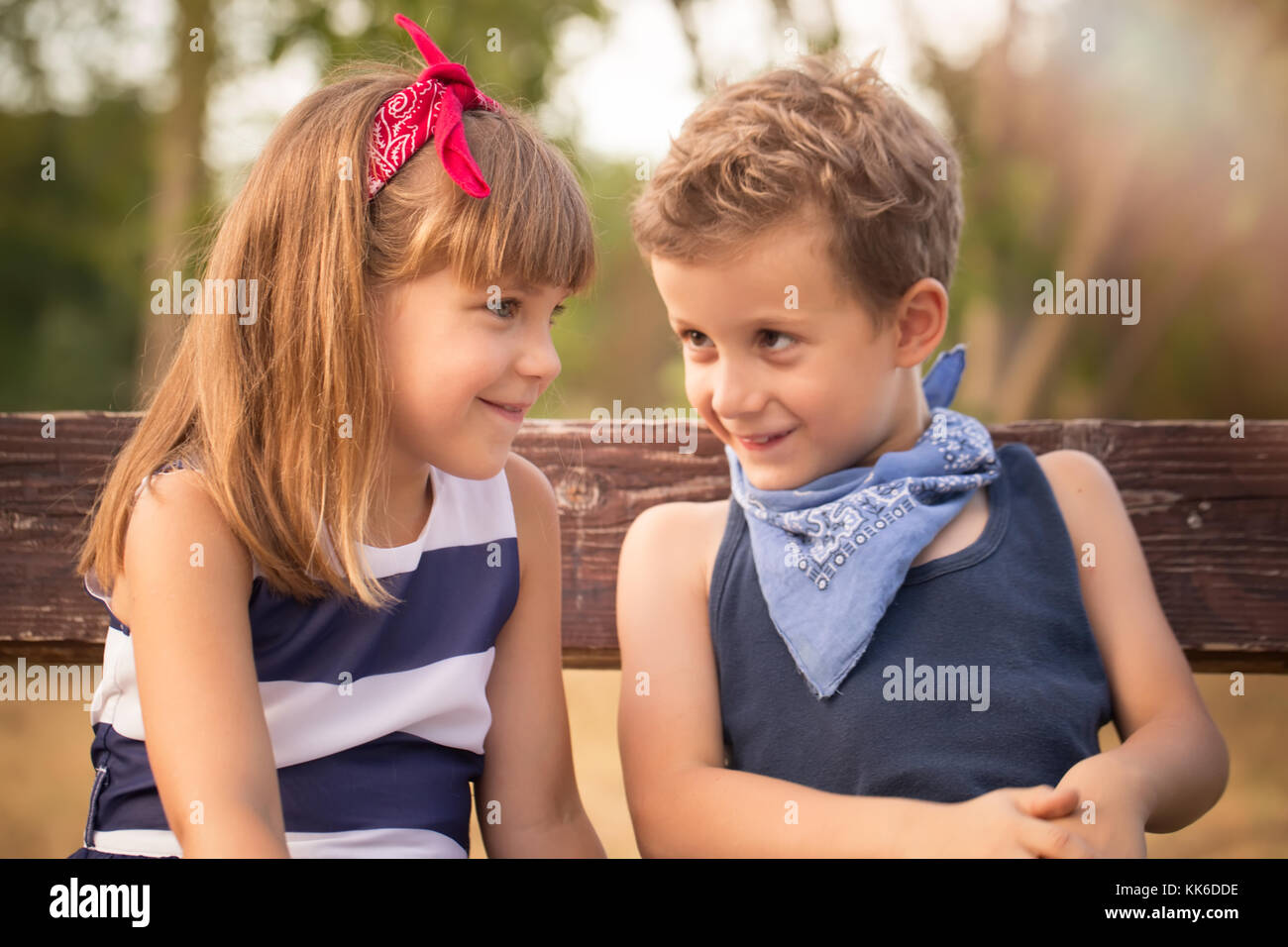 First love. Little sweet boy and a girl sitting on a bench in the park and  having fun. Happy young couple in love outdoor Stock Photo - Alamy