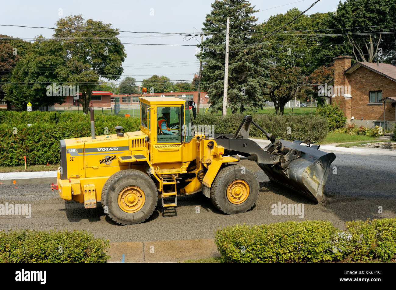 A Volvo L90C Wheel Loader wheeled bulldozer moving gravel on a residential street in Montreal, Quebec, Canada Stock Photo