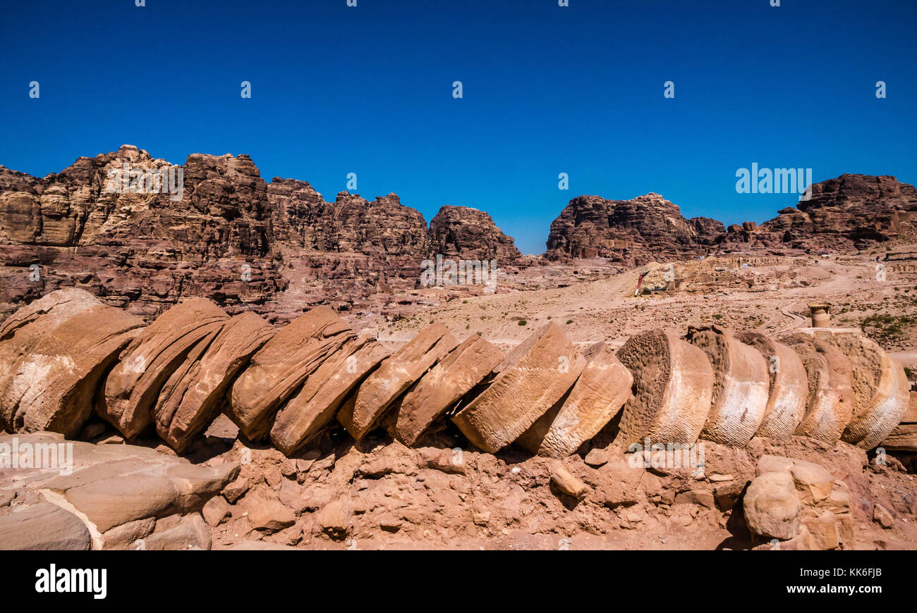 Collapsed sandstone discs of Corinthian column, Petra, Jordan, Middle East, with blue sky and mountains Stock Photo